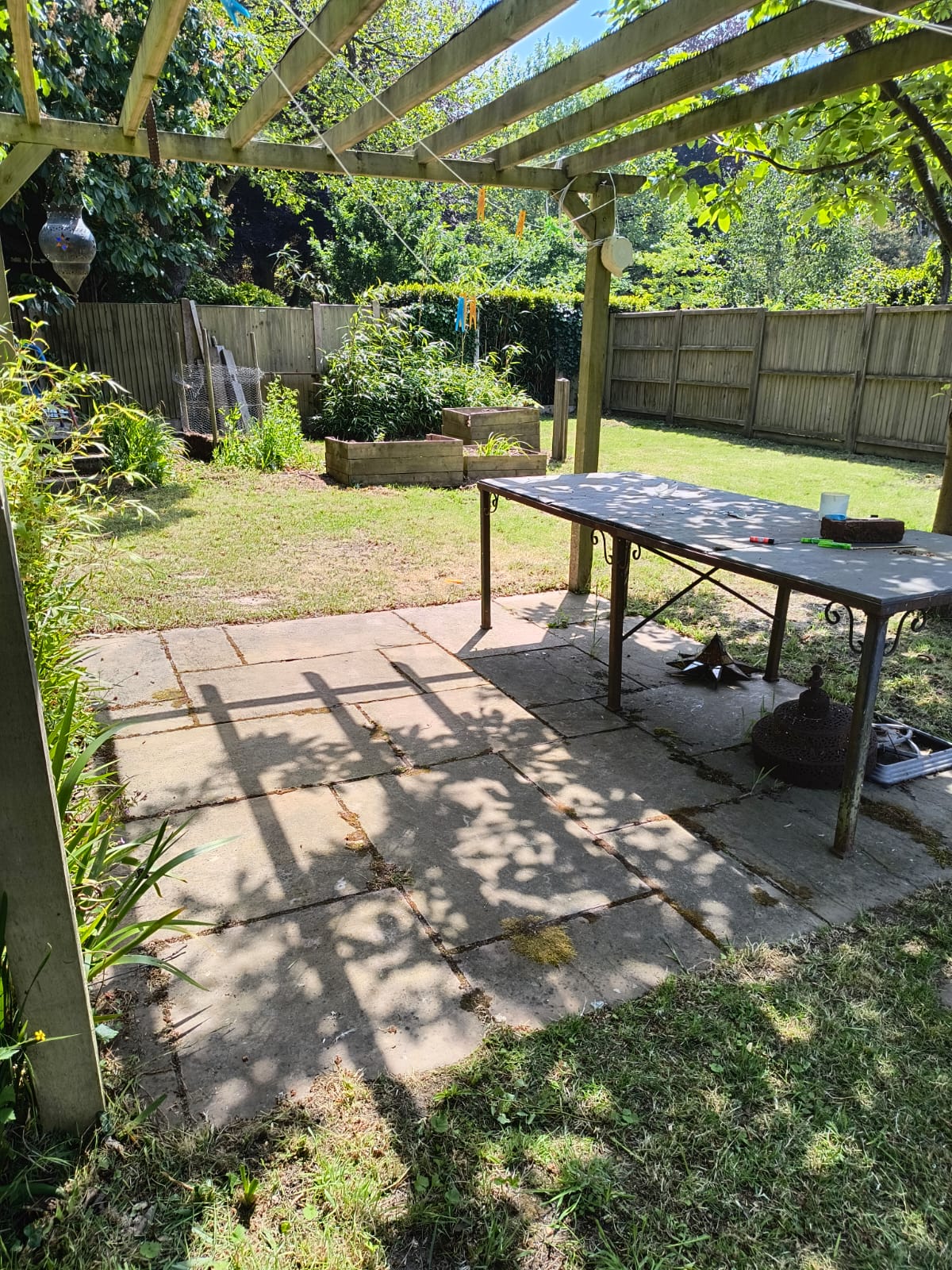 Pergola and patio area at the back of a garden near Walmer after the tidy, table set out under the pergola, mown lawn beyond